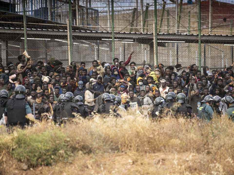 Migrants try to climb over the border fence at Melilla.