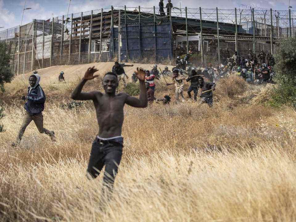 A migrant cheers after crossing the border fence.