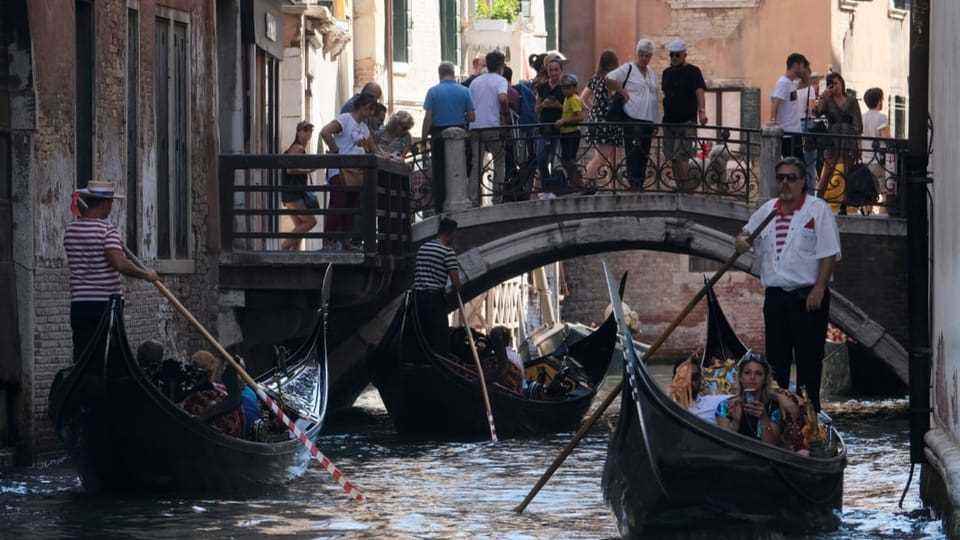 Bridge in Venice full of people, including three gondolas, also with customers
