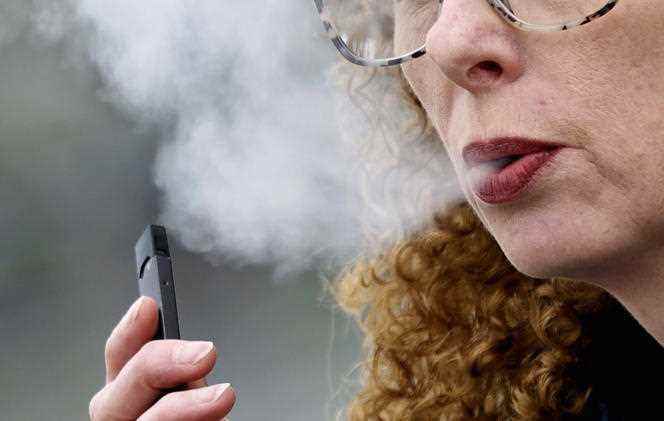 A woman exhales while vaping an e-cigarette in Vancouver, Canada in April 2019. 