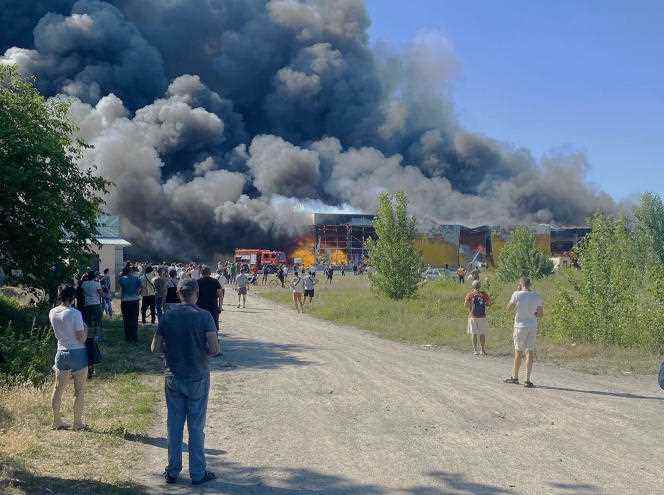 Residents watch the fire in the Kremenchuk shopping center, hit by a Russian missile, June 27, 2022.