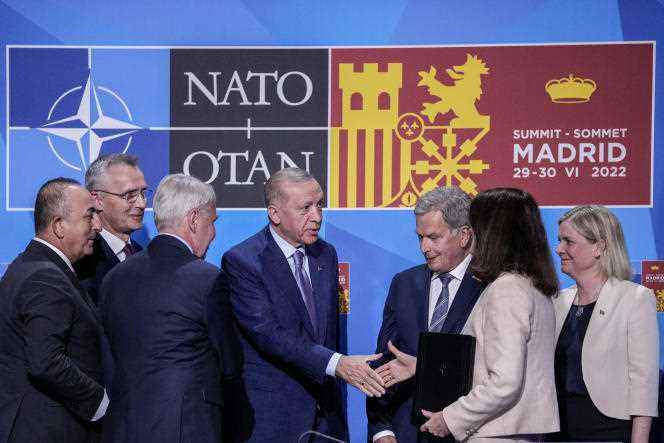 Turkish President Recep Tayyip Erdogan, center, shakes hands with Swedish Foreign Minister Ann Linde during the NATO summit in Madrid, June 28, 2022.
