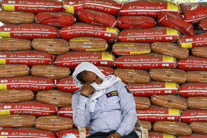 A security guard in front of sacks of wheat at a wholesale grain market in New Delhi on May 18, 2022.