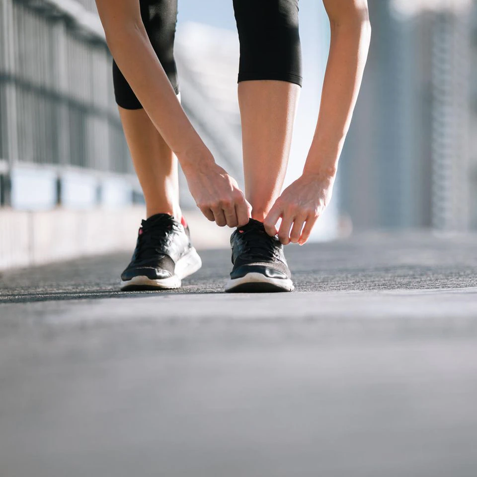 Woman tying sports shoes: These 5 fitness hacks turn your walk into a workout