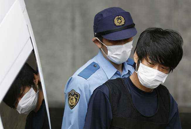 The assassin (right) leaving the Nara police station on July 10. 