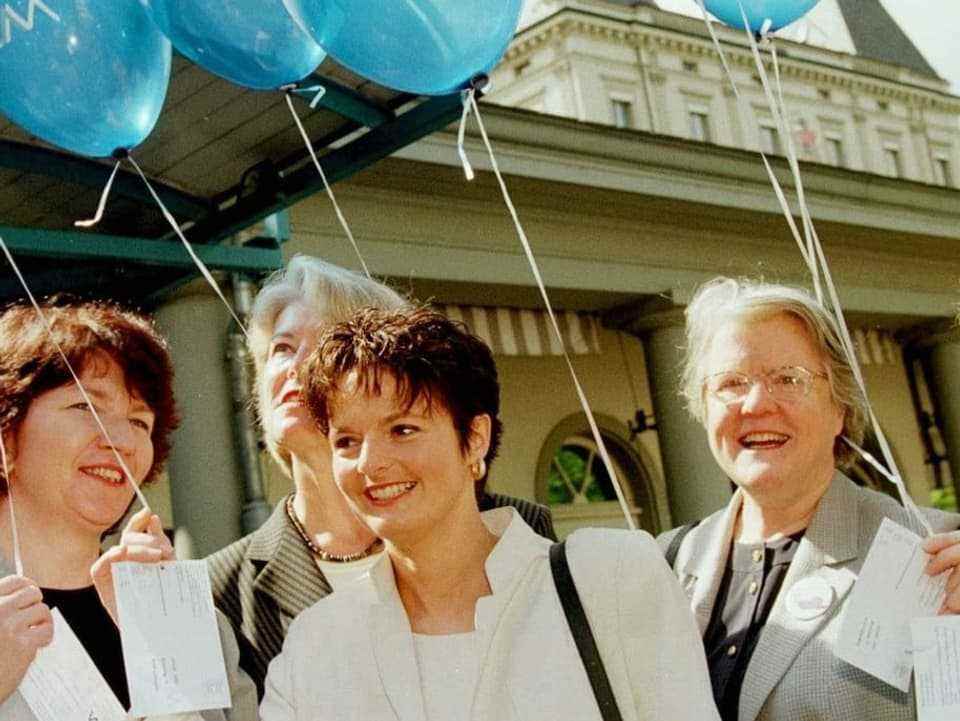 Five middle-aged women with balloons in their hands.