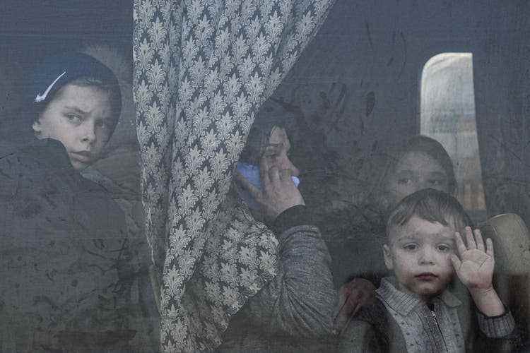 Internally displaced people look out from a bus at a refugee center in Zaporizhia, Ukraine, Friday, March 25, 2022. (AP Photo/Evgeniy Maloletka)