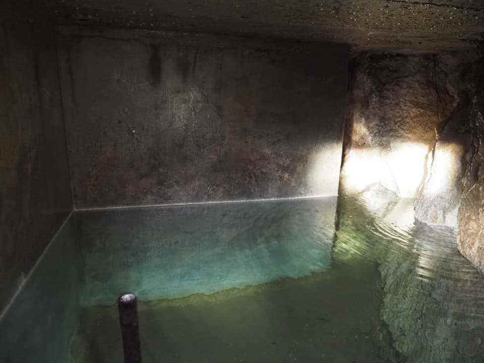 The picture shows the inside of a spring basin, which is half filled with water.