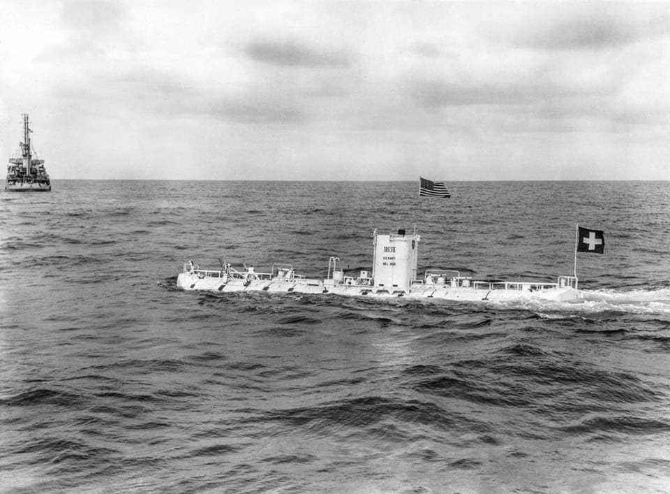 Black and white photo: submarine with US and Swiss flags floating in the water