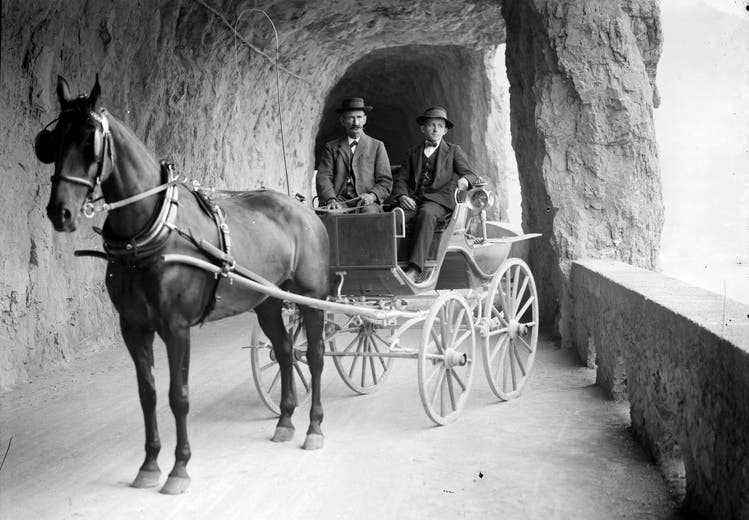 Two men pose in a carriage circa 1920.