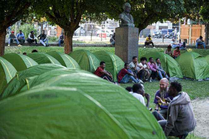 Migrants sit near their tents on Place Daviais in central Nantes as part of a symbolic action on July 3, 2019.