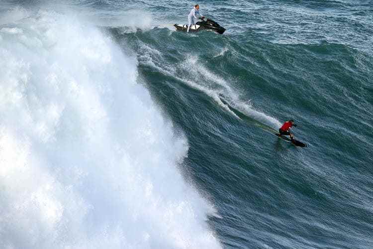 Maya Gabeira surft eine Welle, Sebastian Steudtner fährt den Jetski. Jetzt halten beide den Weltrekord, sie bei den Frauen, er bei den Männern.