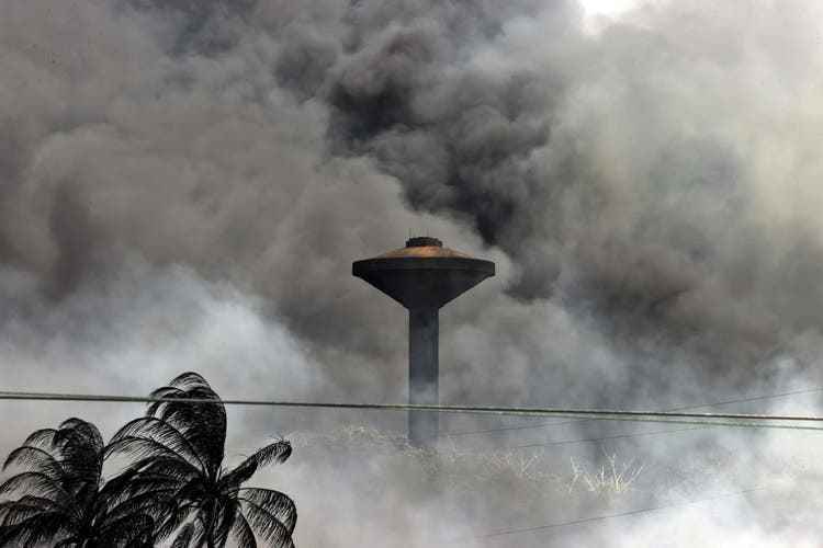 A water tank can be seen through the column of smoke. 