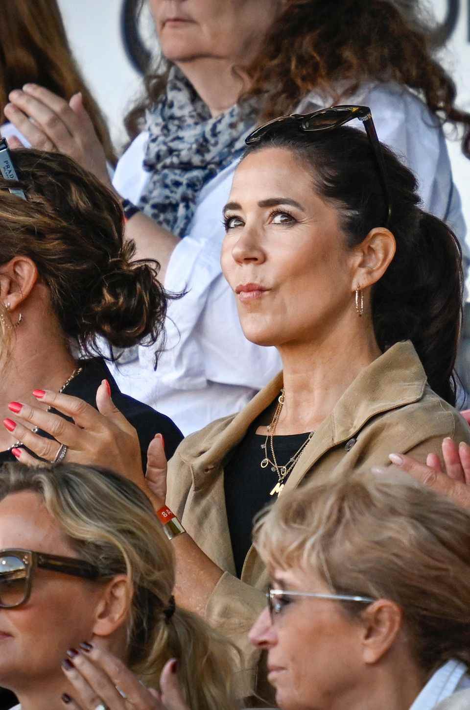 Crown Princess Mary wears a lot of jewelry with her rather simple outfit and has bright red painted fingernails. 