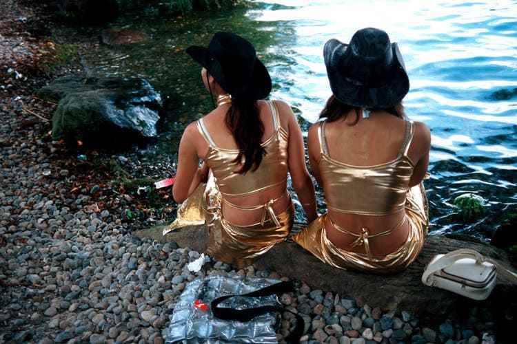 Zwei als Cowgirls verkleidete Mädchen sitzen am See, an der Street Parade 2004.
