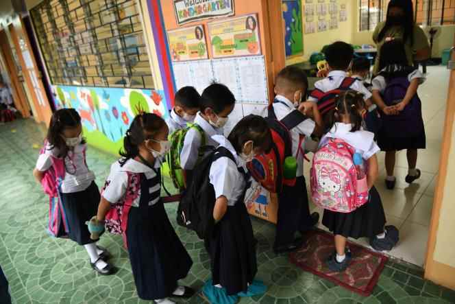 Students wearing masks enter their classroom for the resumption of face-to-face classes in the Philippines, at a school in Quezon City, a suburb of Manila, on August 22, 2022.