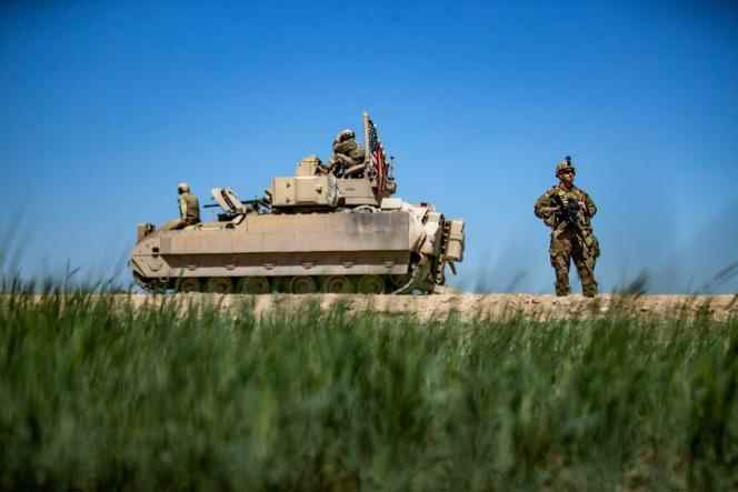 A U.S. soldier stands next to a U.S. Army armored vehicle while on patrol in the countryside of the Kurdish-majority town of Qamishli in Syria's northeast Hasakeh province, on April 20, 2022.