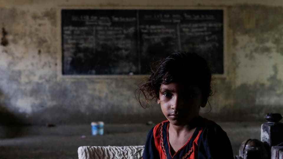 A Pakistani girl sits in an abandoned school to find shelter from the floods.
