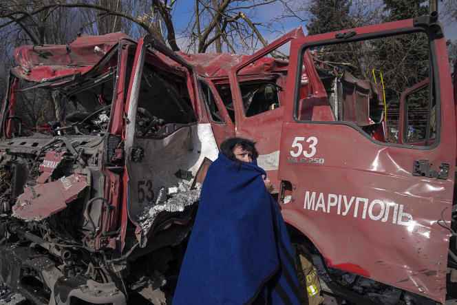 A woman in front of a fire truck destroyed by shellfire.  Mariupol, Ukraine, March 10, 2022.