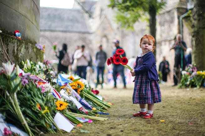 A girl lays flowers in memory of the late Queen outside Holyrood Palace in Edinburgh.