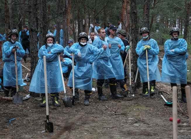 Members of the Ukrainian Civil Protection Service help exhume the bodies.