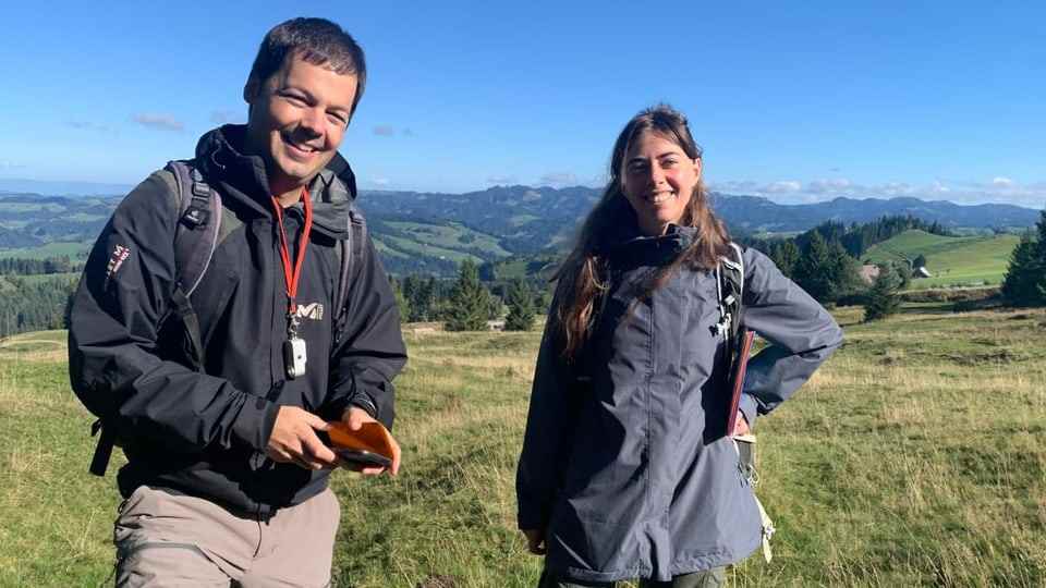 Andrin Gross and his research colleague are standing in a meadow.