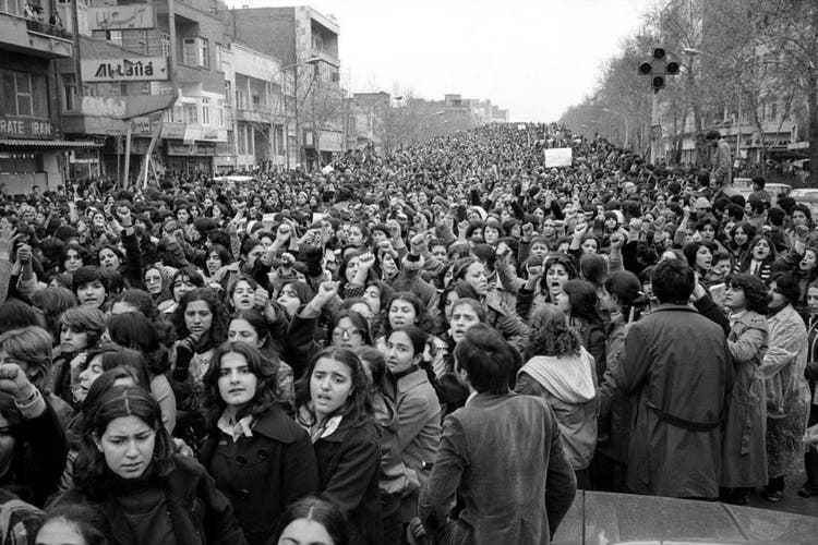On March 8, 1979, crowds of women protest against having to wear a headscarf.  Men have formed lines at the edge to protect the demonstrators from attacks.