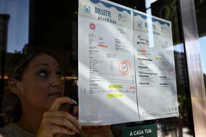 A woman displays energy bills on the windows of her bar in Milan on September 9.  Over one year, the increase is more than 392%.