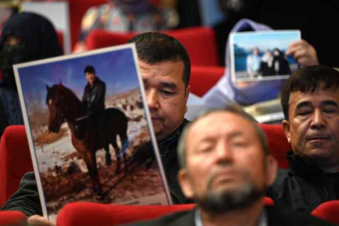 Members of the Uyghur Muslim minority show photos of their detained relatives in China, during a press conference in Istanbul on May 10, 2022.