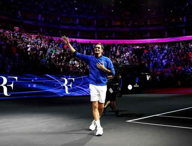 Roger Federer waves in the arena