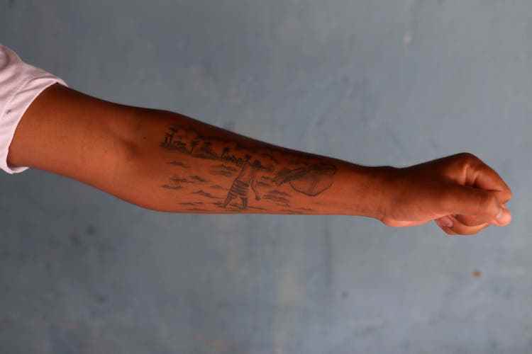 Uine Lopes presents his tattooed arm showing his grandfather fishing. 
