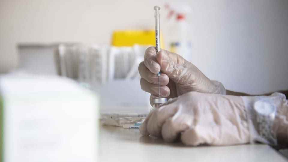 A hand draws up a vaccination syringe.