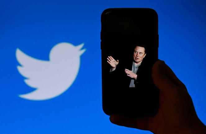 A photo of Elon Musk on a phone with the Twitter logo displayed in the background, in Washington, October 14, 2022.
