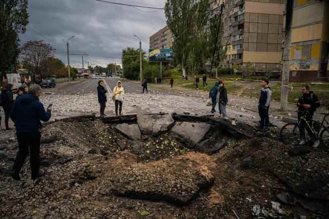 Residents examine a crater caused by a missile strike in Dnipro, October 10, 2022.