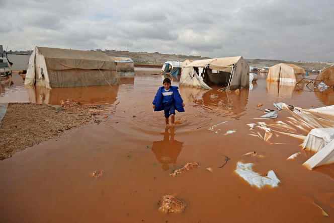 A Syrian child walks through the flooded alleys of a camp for displaced people in the north of the country on the border with Turkey, in the province of Idlib, on January 19, 2021. 