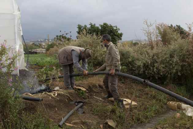 Ahmad Ajaj's cousin and his employee repair pipes before watering the vegetables they planted in the village of Haryk, near the town of Bebnine, in Akkar, north Lebanon, November 1, 2022. Ahmad Ajaj and his cousin installed a water filter that cleans the water before watering.