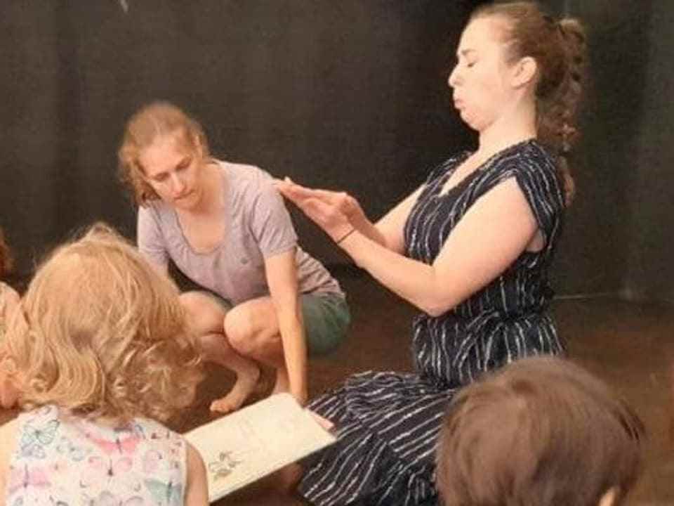 Two theater workers read children from a book.