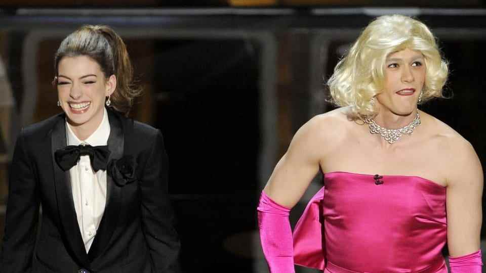 Anne Hathaway laughs alongside James Franco who is wearing women's dresses.  The two hosted the Oscars in 2011.