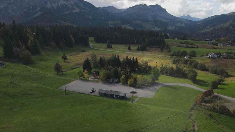 Mountains in the background, lush meadows and in the middle a concrete square with a long hut.