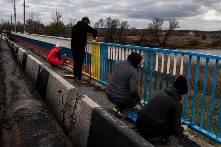 Freiwillige übermalen die Farben Russlands am Geländer einer Brücke. Sie wollen damit zeigen, dass das Land hier der Ukraine gehört.
