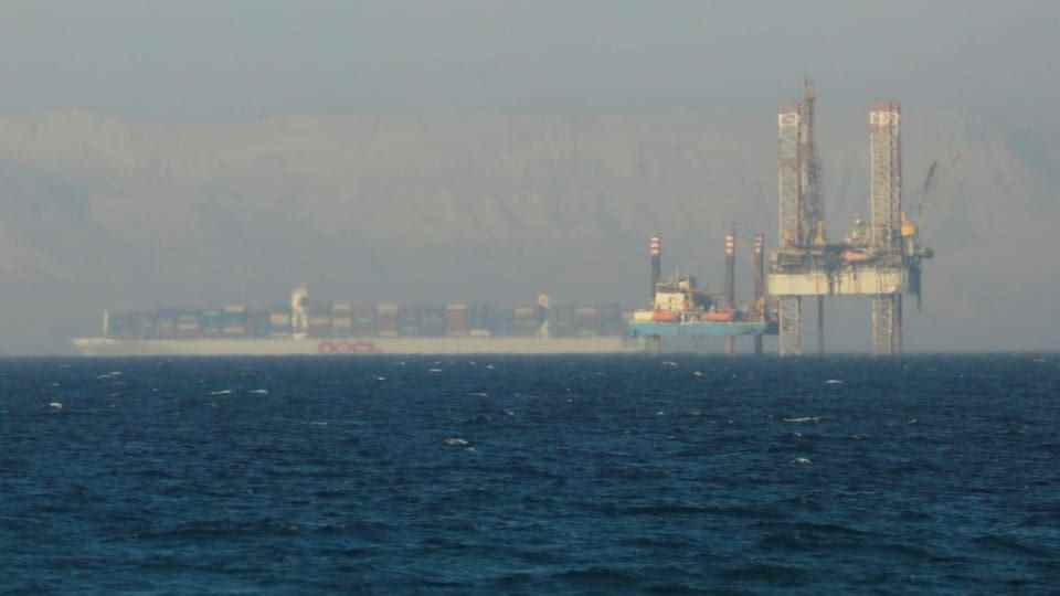 Ship passes an oil platform at sea.