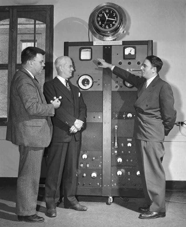 Bureau of Standards (now the National Institute of Standards and Technology) physicist Harold Lyons (right) explains how an atomic clock works.