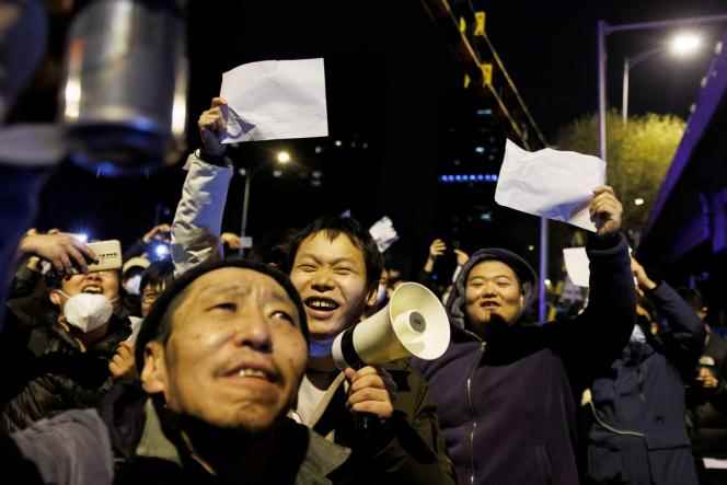 Demonstrators hold white sheets of paper in protest against coronavirus restrictions, in Beijing on November 28, 2022.