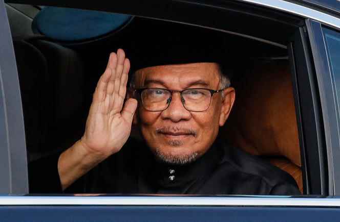 Malaysia's new Prime Minister Anwar Ibrahim waves from his car as he arrives to take part in the swearing-in ceremony at the National Palace in Kuala Lumpur on November 24, 2022. 