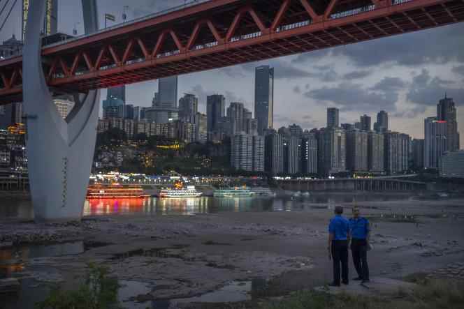 Security officers at the edge of the dry bed of a tributary of the Yangtze River from which they have just evacuated onlookers, in the municipality of Chongqing, southwest China, August 20, 2022. The widespread drought which affected large parts of Europe, the United States and China this summer has been made twenty times more likely by climate change, according to a new study.