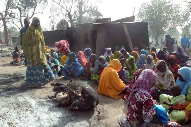 Women sit around the carcass of a cow after a jihadist group attacked their village in northeastern Nigeria on January 31, 2016.