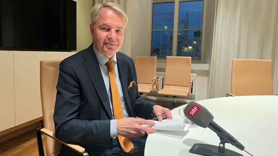Haavisto at a table, in front of him a microphone with the SRF logo.