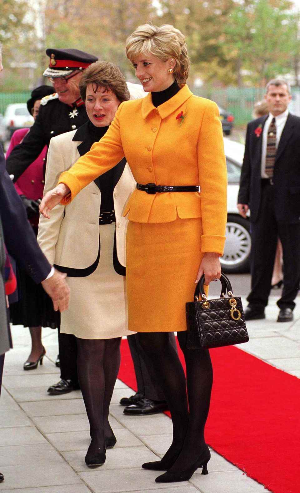 Princess Diana wearing a Versace orange suit and carrying her beloved Dior bag in Liverpool, November 1995