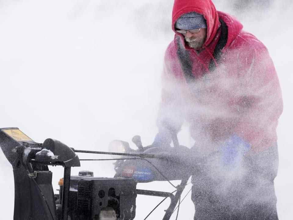 A man clears snow with a machine