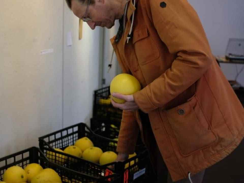 A man holds a huge citrus fruit in his arms.